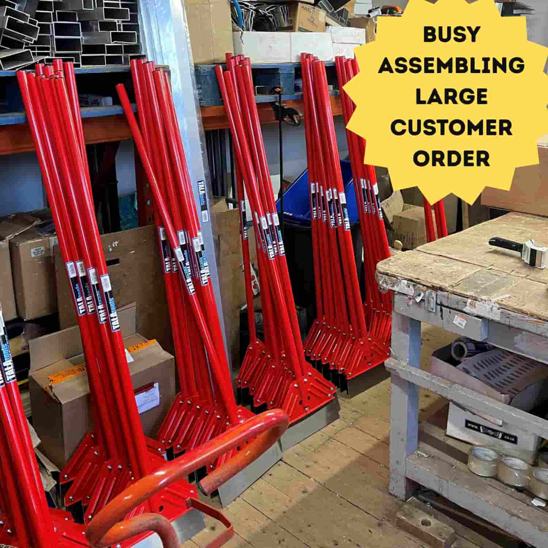 Red metal frames in a warehouse with a sign indicating assembly of a customer order.