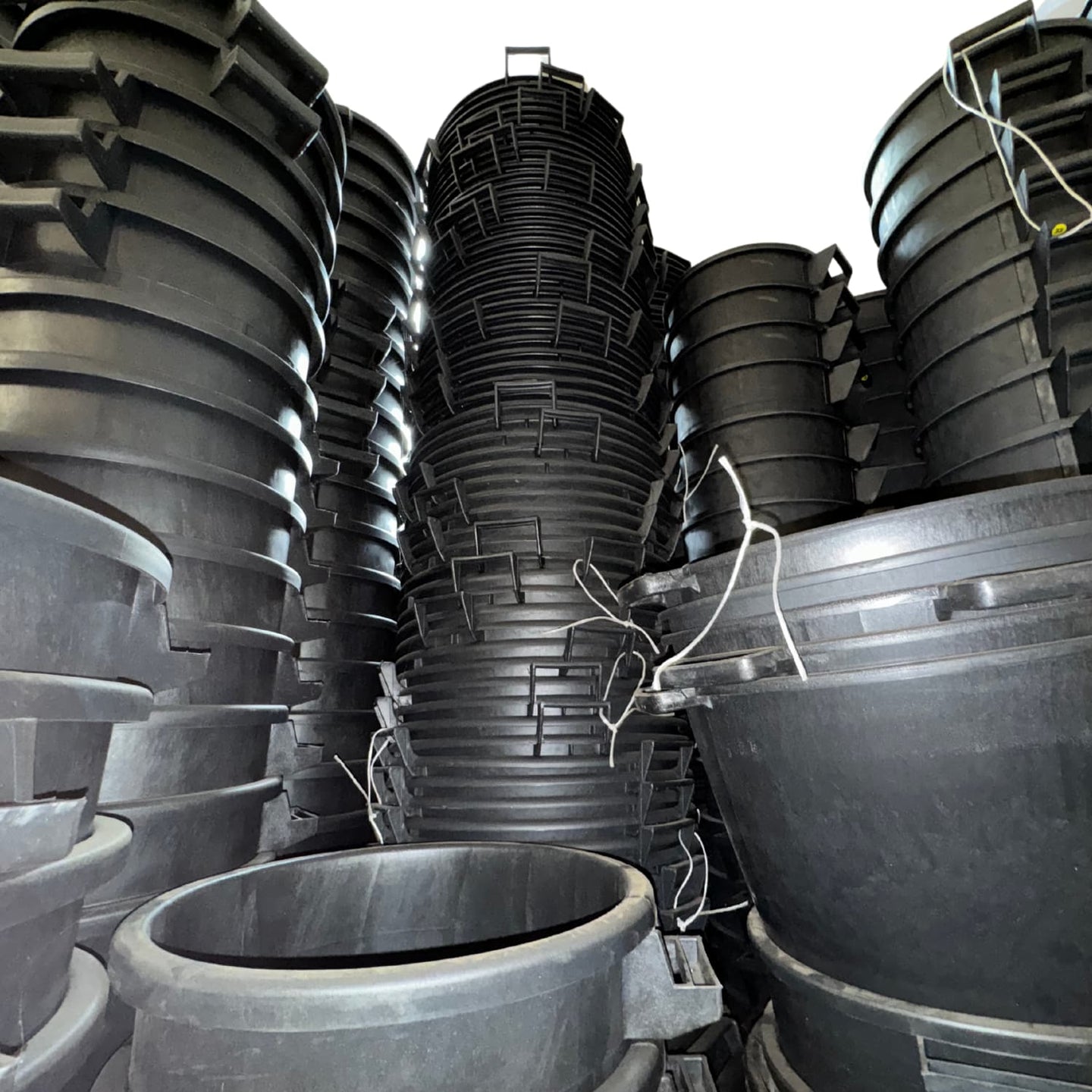 Stacks of large black plastic containers in a warehouse setting