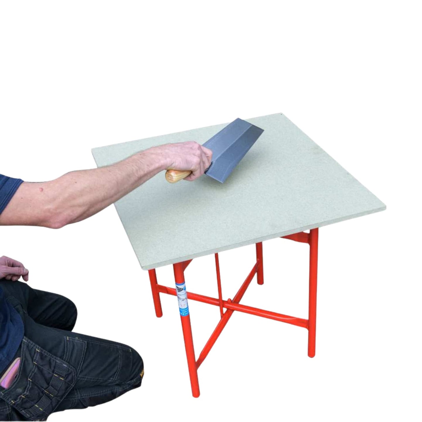 Man kneeling down using a hand tool on a red plastering table.