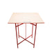 Table with a beige top and red metal frame on a white background