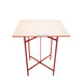 Table with a beige top and red metal frame on a white background