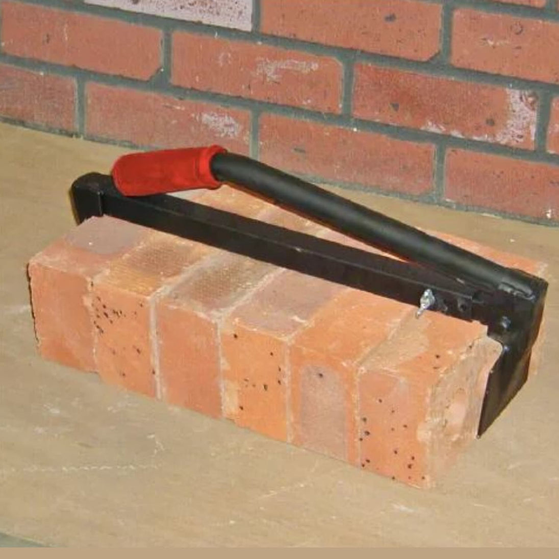 Bricklaying trowel with red handle on a brick surface