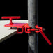 Red clamp tool attached to a metal pole on a black background