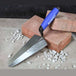 Trowel with blue handle on bricks and stones