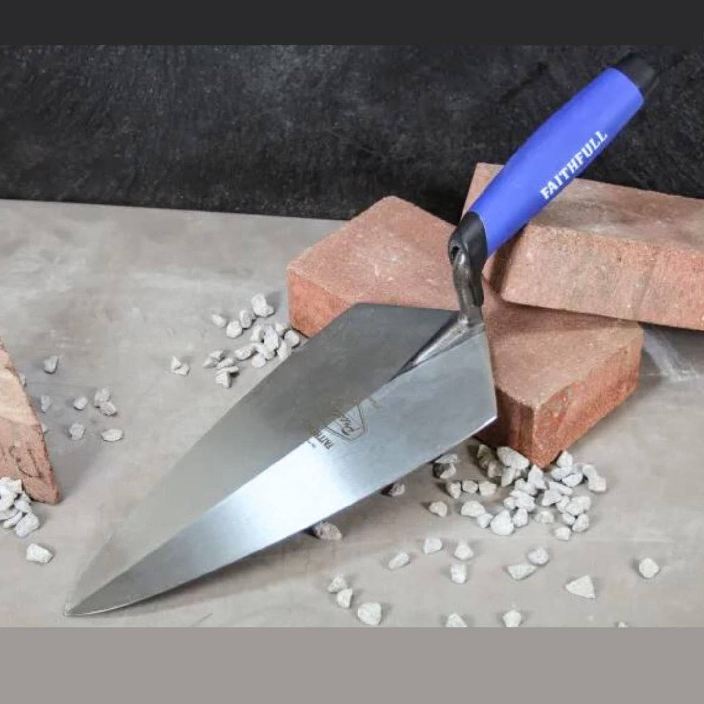 Trowel with blue handle on bricks and gravel