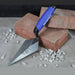 Brick trowel with blue handle on bricks and gravel