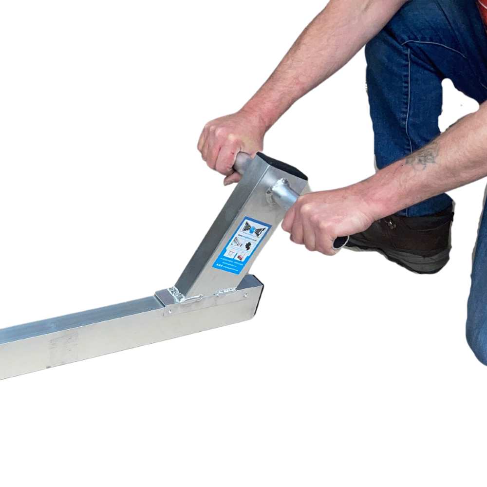 man kneeling down using tamping beam handles short